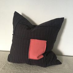 a black and red striped pillow with a pink patch on the front, sitting on a bed