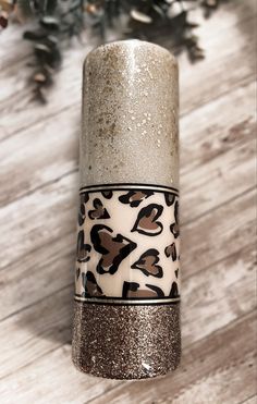 a silver and white vase with leopard print on the side sitting on a wooden floor