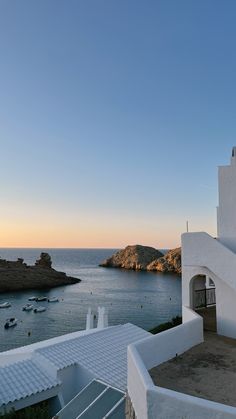 the sun is setting over an ocean with white buildings and steps leading up to it