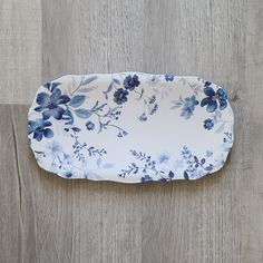 a blue and white flowered tray sitting on top of a wooden floor next to a wall