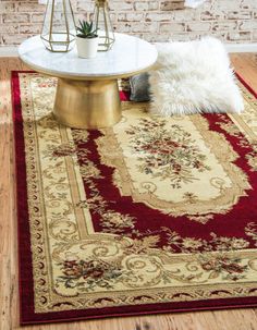 a living room with a rug, coffee table and potted plant