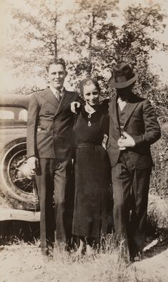 an old black and white photo of three people standing next to each other in front of a car