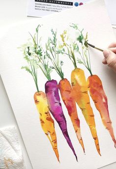 a person is painting three carrots with watercolor pencils on paper, and the other hand is holding a paintbrush