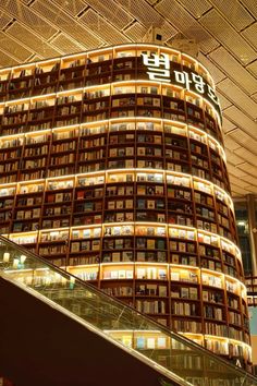 an escalator in front of a tall building with many books on it's sides