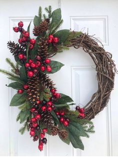 a wreath with berries and pine cones on the front door