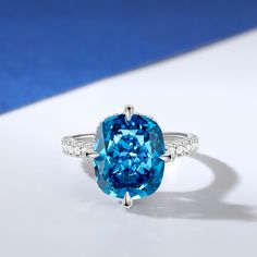 This is a stunning blue stone ring that exudes elegance and sophistication. The centre of the ring is set with a large, captivating blue stone that commands attention with its deep, enchanting hue. The sparkling centre stone is also set with a hidden halo of smaller round stones, and the glittering stone-set band adds to the brilliance of this chic ring. The smooth and delicate design ensures a comfortable fit while showcasing the beauty of the central blue stone.Carat Weight: 6.29 ctStone Size: 10*12 mmStone Type: Jeulia® StoneNumber of Stones: 1 Stone Color: Aquamarine BlueStone Shape: Fat OblongCarat Weight: 1.381 ctStone Size: 1,1.2,1.7,0.8 mmStone Type: Jeulia® StoneNumber of Stones: 68 Stone Color: Diamond WhiteStone Shape: RoundWeight: 2.9 gWidth: 1.9 mmHeight: 10 mmThickness: 1.5 m Blue Aquamarine Jewelry With Center Stone, Turquoise Sapphire Gemstone Promise Ring, Turquoise Sapphire Promise Ring, Blue Cubic Zirconia Diamond Ring With Center Stone, Blue Aquamarine Fine Jewelry, Dazzling Blue Sapphire Ring With Accent Stones, Blue Sapphire Promise Ring With Gemstone Accents, Blue Sapphire Ring With Gemstone Accents For Promise, Elegant Sapphire Crystal Ring With Diamond