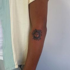 a man's arm with a tattoo on it that has a sun in the middle