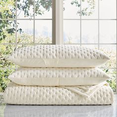 three pillows stacked on top of each other in front of a window with trees outside