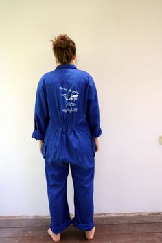 "Vintage blue chore coveralls from Israeli flight school printed in Hebrew on the back and front...\" Amal Ramat David Building the future\" with an F16 airplane drawing on the back panel, pockets with velcro opening, zips down the front, elastic waist on the back, soft cotton. an oversize and loose fit can be worn by both men and women. aside from minor signs of wear...The back hem of the pants is worn, otherwise, good vintage condition clean ready to wear. **Model is 5'8\" and a size s/m for r Blue Utility Jumpsuits And Rompers With Relaxed Fit, Blue Relaxed Fit Utility Jumpsuit Or Romper, Blue Utility Jumpsuit With Relaxed Fit, Blue Relaxed Fit Utility Jumpsuits And Rompers, Blue Utility Jumpsuits And Rompers For Work, Blue Bib Front Jumpsuit For Workwear, Blue Bib Front Jumpsuits And Rompers For Work, Blue Workwear Overalls, Blue Cotton Long Sleeve Denim Jumpsuit