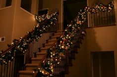 christmas lights are on the stair railing and garland is hanging from the bannister