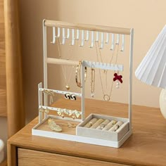 a white jewelry box sitting on top of a wooden table next to a lamp and vase