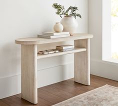 a white vase sitting on top of a wooden table next to a book and two books