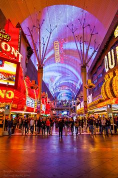 the inside of a shopping mall with many people walking around and lights in the ceiling