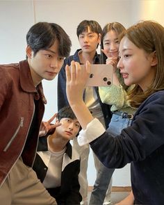 a group of young people standing around each other taking pictures with their cell phones in front of them