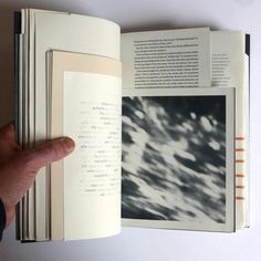 a hand is holding an open book with black and white images