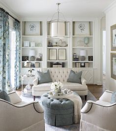 a living room with white furniture and blue accents