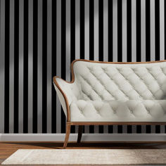 a white couch sitting on top of a wooden floor next to a black and white striped wall