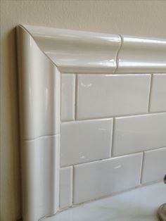 a close up of a faucet in a bathroom with white tiles on the wall