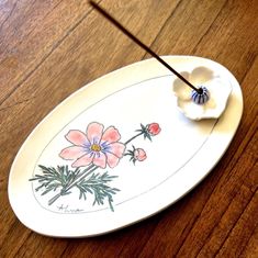 a plate with flowers painted on it sitting on a wooden table next to chopsticks