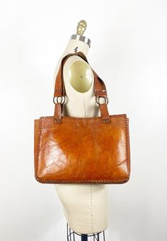 "Item description: 1970s brown genuine soft leather filled bag. Magnetic button closure. Open interior with no pockets. One exterior compartment. Shoulder style straps. This bag does have some wear and patina throughout but that's what makes it beautiful.  Measurements: Length: 10\" Width: 13.5\" Depth:3\" Strap drop: 10\" Please see item description and photos for any flaws. All vintage is sold \"AS IS\" feel free to message me for any questions you have or for any additional photos." Vintage Brown Bag For Everyday Use, Vintage Satchel Shoulder Bag For Everyday, Retro Brown Satchel With Adjustable Strap, Vintage Light Brown Bags For Everyday Use, Vintage Light Brown Bag For Everyday Use, Everyday Vintage Satchel Shoulder Bag, Retro Brown Satchel For Everyday Use, Retro Brown Tote Shoulder Bag, Retro Vintage Brown Leather Bags