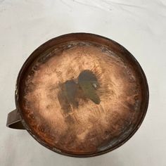 an old metal pan with a bird on it's side sitting on a white surface