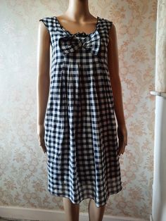 "Vintage smock style dress in black and white  gingham.  There is a small ruffle at the neck line and a large bow,  small pleats with the dress flaring from the bust.  It has no sleeves and is lined in black cotton. Bust;   32\" Length from shoulder;      35\"      Made by   MADAME A PARIS        100%  cotton" Summer A-line Plaid Dress, Sundress With Ruffles For Picnic, Ruffled Sundress For Picnic, Ruffled Sundress For Picnics, Summer Vintage A-line Sundress, Gingham Dress With Ruffles For Picnic, Gingham Dresses With Ruffles For Picnic, Picnic Gingham Dress With Ruffles, Plaid Ruffled Dress For Picnic