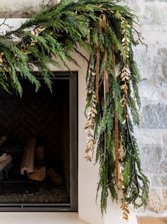 a fireplace decorated with greenery and gold ribbons