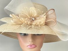 "The featured listing is a dressy wide brimmed pale gold straw hat. A  crinkle organza pale gold flower sits in the center of the hat. Sinamay loops in ivory and tan are set around the center flower. A very large multi layered ivory crinoline bow extends out and over the brim of the hat.  All the elements combining  making the hat so interesting and softly dramatic. This  hat is  beautiful for the Kentucky Derby or  for  Sunday  Church.  It is also perfect for an Easter Hat, Tea Party hat,Weddin Chic Beige Straw Hat For Garden Party, Chic Beige Sun Hat For Garden Party, Gold Brimmed Mini Hat For Wedding, Gatsby Style Summer Wedding Fascinator, Summer Wedding Gatsby Style Fascinator, Spring Church Hat With High Crown, Adjustable Vintage Straw Hat For Weddings, Elegant High Crown Top Hat For Wedding, Elegant Gold Sun Hat For Summer