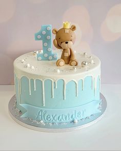 a blue and white birthday cake with a teddy bear on top, the number one