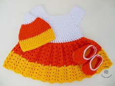 a crocheted baby dress and hat with shoes on the bottom, sitting on a white surface