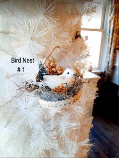 a bird nest hanging from the side of a white christmas tree