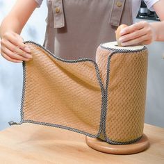 a woman is holding a roll of fabric on top of a table