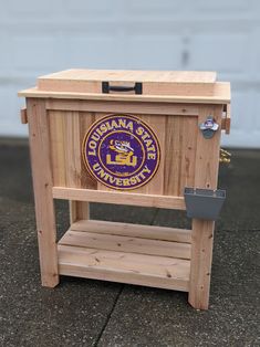 a wooden box with a purple and yellow logo on the front sitting on top of a sidewalk