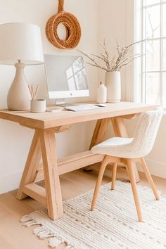 a wooden desk with a computer on top of it next to a white chair and lamp