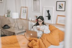 a woman sitting on her bed looking at her laptop