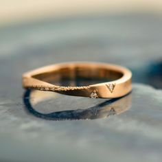 a gold wedding band with two diamonds on the side, sitting on top of a table