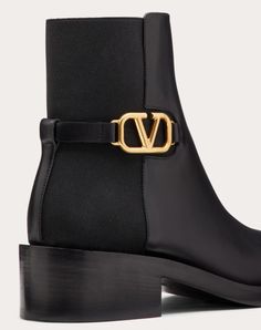 Valentino Garavani calfskin ankle boot with VLogo Signature embellishment. - Antique brass-finish VLogo Signature accessory - Tonal elastic - Internal side zip - Leather sole with non-slip rubber insert - Heel height: 30mm/1.2 in. - Made in Italy Designer Chelsea Boots With Reinforced Heel In Calf Leather, Designer Calf Leather Chelsea Boots, Luxury Calf Leather Chelsea Ankle Boots, Designer Chelsea Ankle Boots For Work, Luxury Chelsea Boots For Work, Woman In Black, Brass Finish, Valentino Garavani, Online Boutique