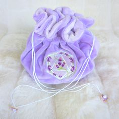 This lavender multi pocket dice bag is made with two shades of purple plush fabric. It is soft to the touch and will keep your dice nice and cozy. The embroidered design on the front features a D20 with swirling blooms of lavender surrounding it. The bag has strong cord drawstrings accented with purple butterfly charms at the ends. Inner bag space is about 9 x 4.5 inches, plenty of room for several sets of dice, there are 6 inner pockets that will hold 3 to 4 standard dice sets and 1 large middl Purple Embroidered Bag For Gift, Handmade Purple Bags For Gifts, Handmade Purple Bags As Gifts, Purple Bag, Dice Bag, Plush Fabric, Purple Butterfly, Butterfly Charm, Embroidered Design