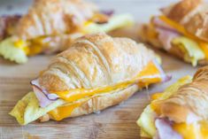 croissants with ham and cheese on them are sitting on a cutting board