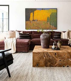 a living room filled with furniture and a large painting on the wall above it's coffee table