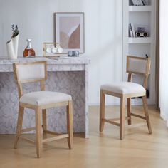 two wooden chairs sitting in front of a marble counter