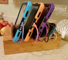 four cell phones are sitting on a wooden stand with cords attached to the phone holders