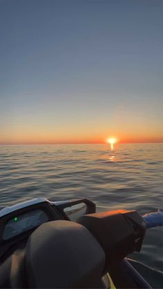 the sun is setting over the ocean as seen from a small boat in the water