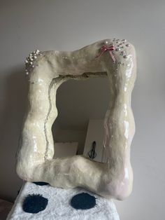 a white sculpture with black dots on it and a mirror in the shape of a hand