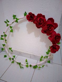 a wreath made out of fake red roses and ivy on the side of a wall