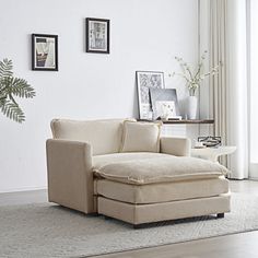 a living room with a couch and chair next to a plant on the floor in front of a window