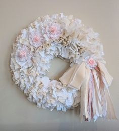 a white wreath with pink flowers hanging on the wall