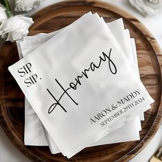 three napkins with the names of two people on them sitting on top of a wooden plate