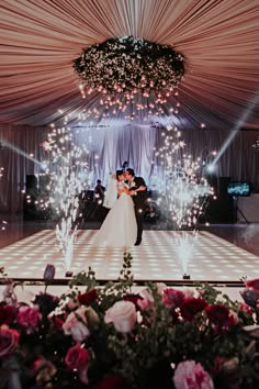 a bride and groom standing in front of a dance floor with sparklers on it