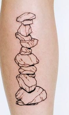 a black and white photo of a person's leg with a stack of rocks on it